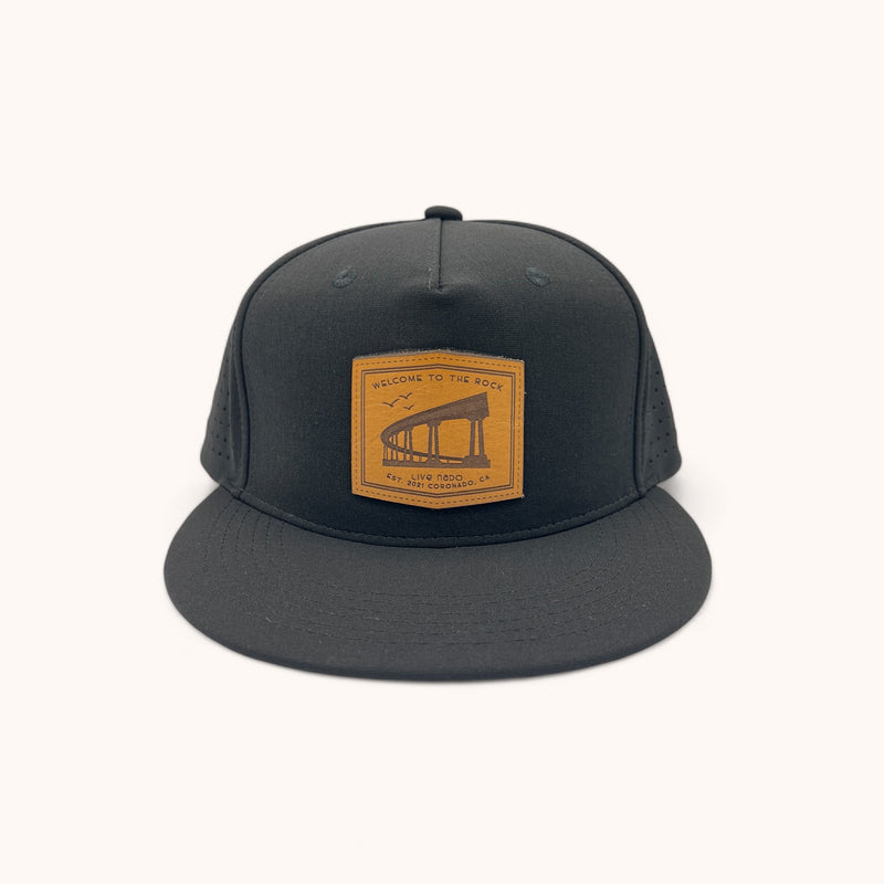 black flat brim trucker with a welcome to the rock leather patch from coronado california