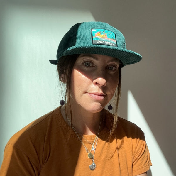 Woman wearing teal corduroy surf cap with a teal pelican patch to remind you of Coronado beach