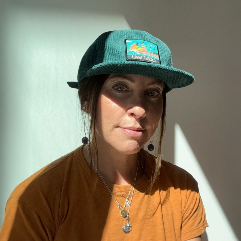 Woman wearing teal corduroy surf cap with a teal pelican patch to remind you of Coronado beach