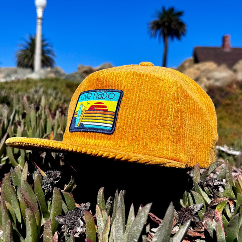 Mustard yellow corduroy unstructured surf cap with flat brim sitting on the beach in Coronado