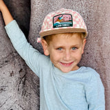 Boy wearing pink checkered baseball cap also called surf cap, flat brim with pelican patch